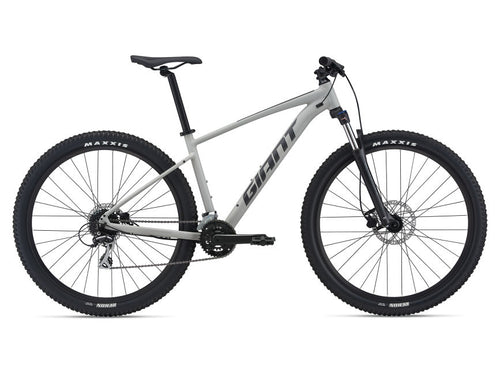 A gray mountain bike with black tires and accents, showcasing the full bicycle from a side angle including the frame, wheels, and components.