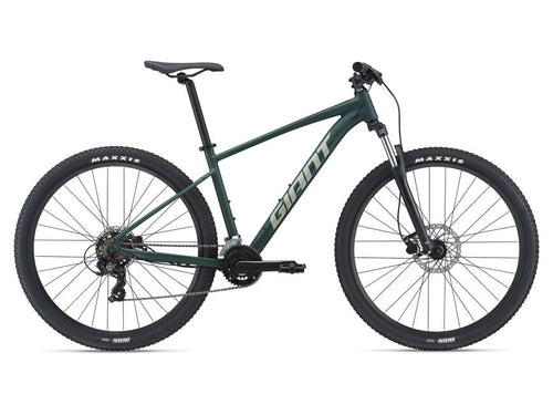A trekking green mountain bike with metallic finish, equipped with disc brakes, a Shimano cassette, and Maxxis tires.
